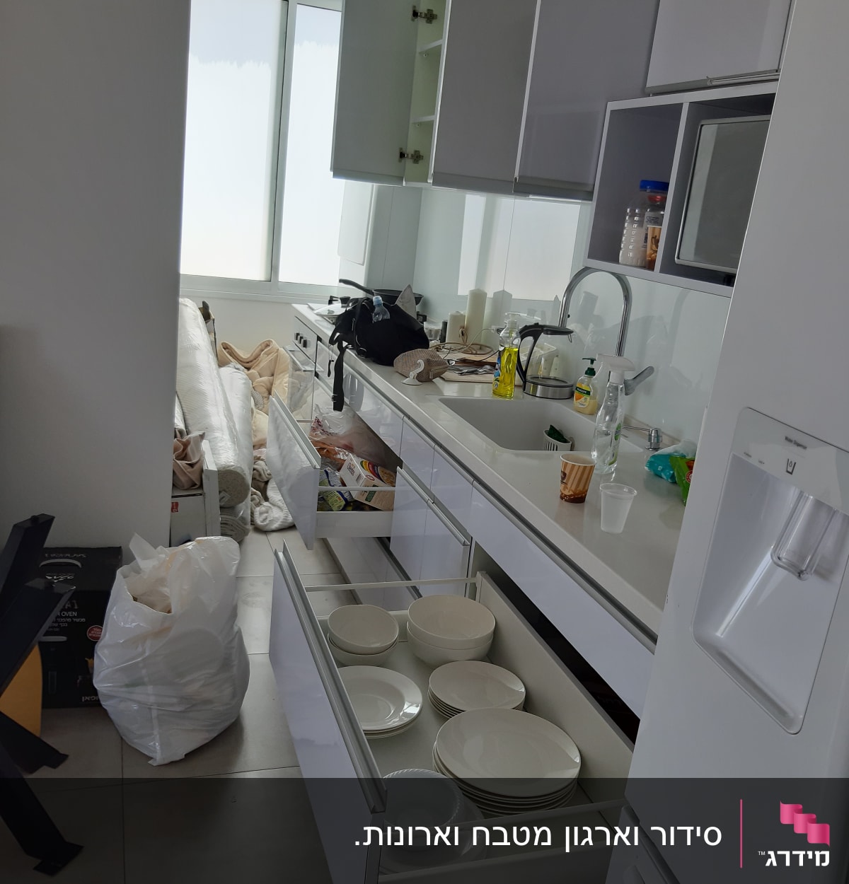 מגירות פתוחות עם צלחות, כיור עם כלים, בקבוקי ניקוי